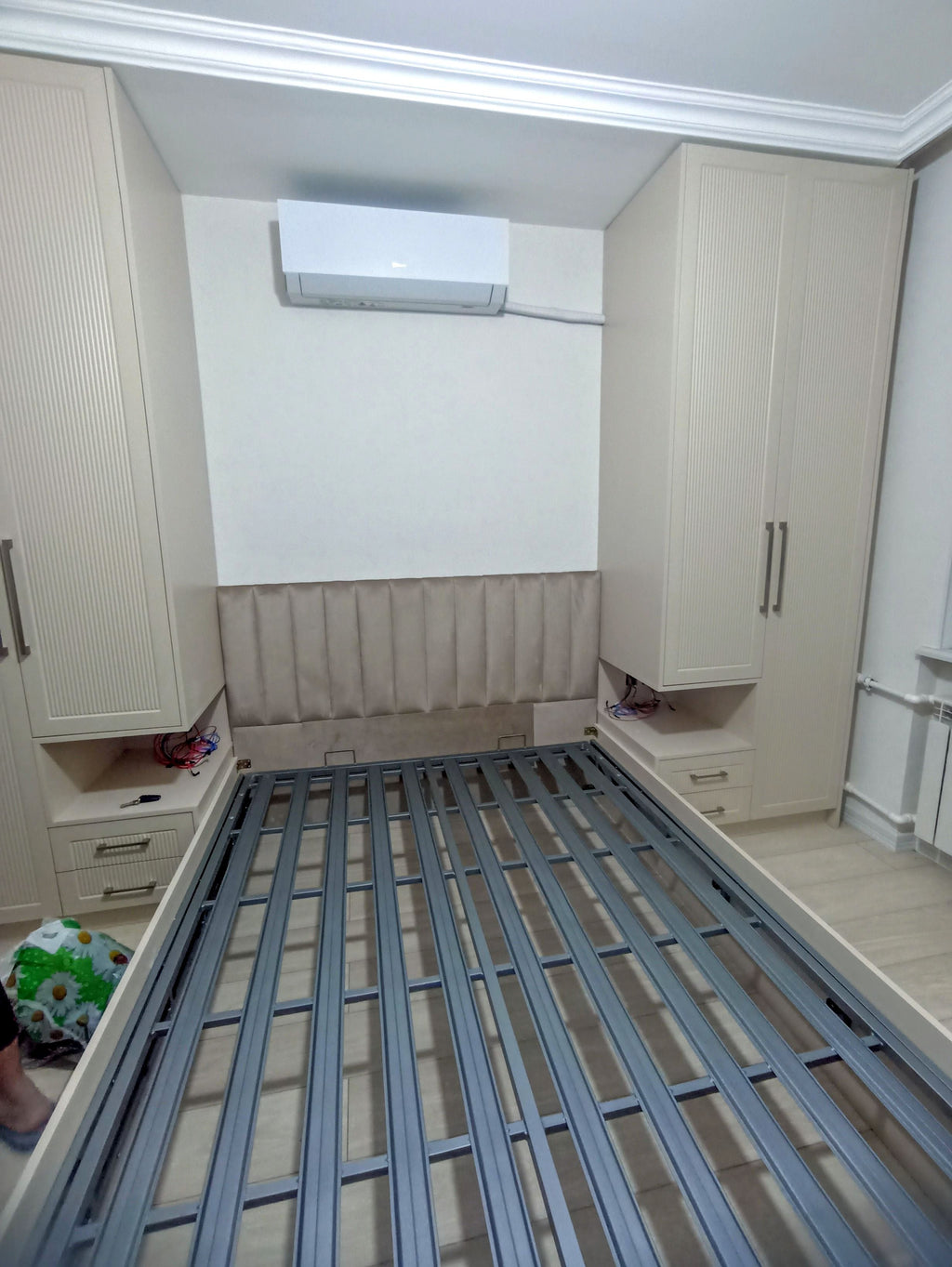 İki hündür dolab arasında bej başlıqlı çarpayı və yan modullar